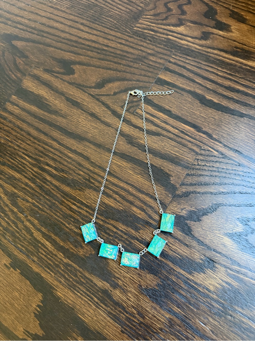 Silver-tone chain linked with emerald-cut, opalescent rectangular gems.